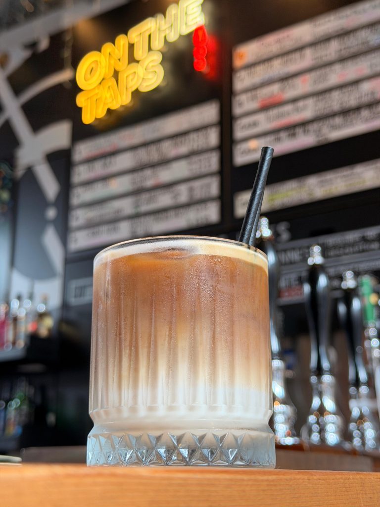A cocktail served in front of the Perfect Hive tap wall.